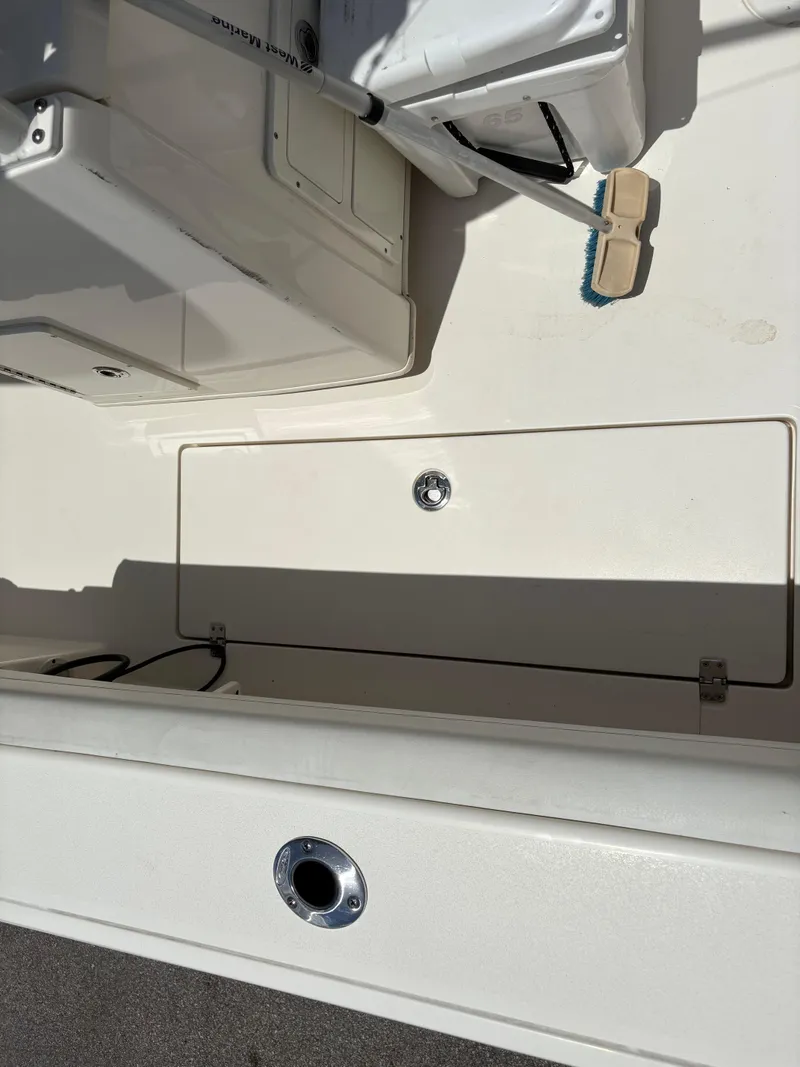 Slide: The Image of 2022 Cobia 301 Center Console boat deck with storage compartment and cleaning brush. - 29