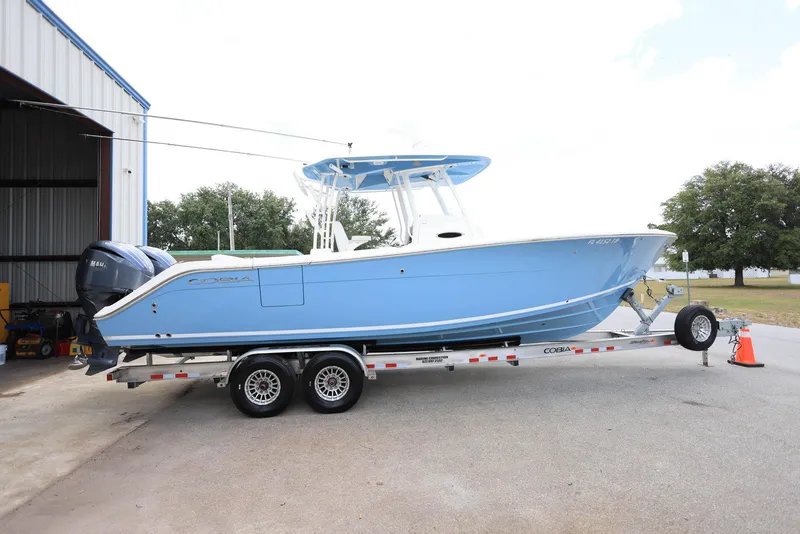 Slide: The Image of 2022 Cobia 301 Center Console boat on trailer, parked outside a building. - 3
