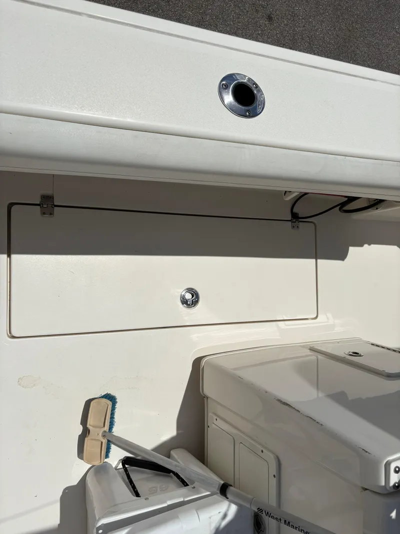 Slide: The Image of 2022 Cobia 301 Center Console boat interior with storage compartment and cleaning brush. - 32