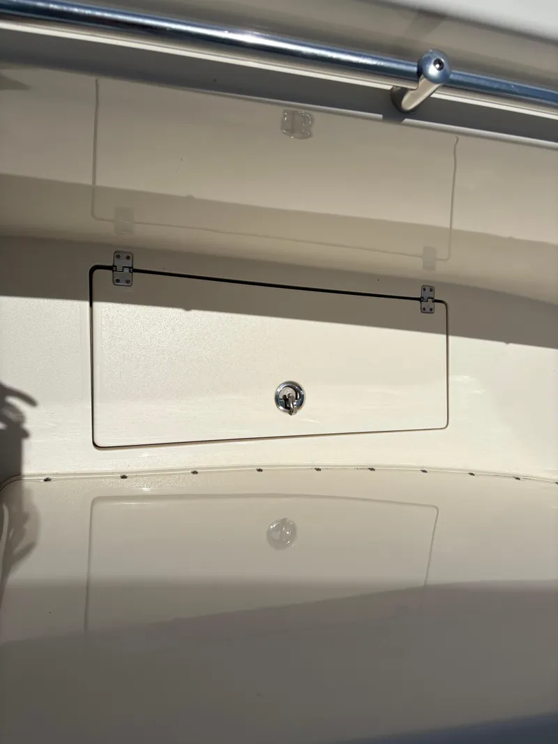Slide: The Image of 2022 Cobia 301 Center Console storage compartment with latch, featuring sleek design and stainless steel railing. - 33