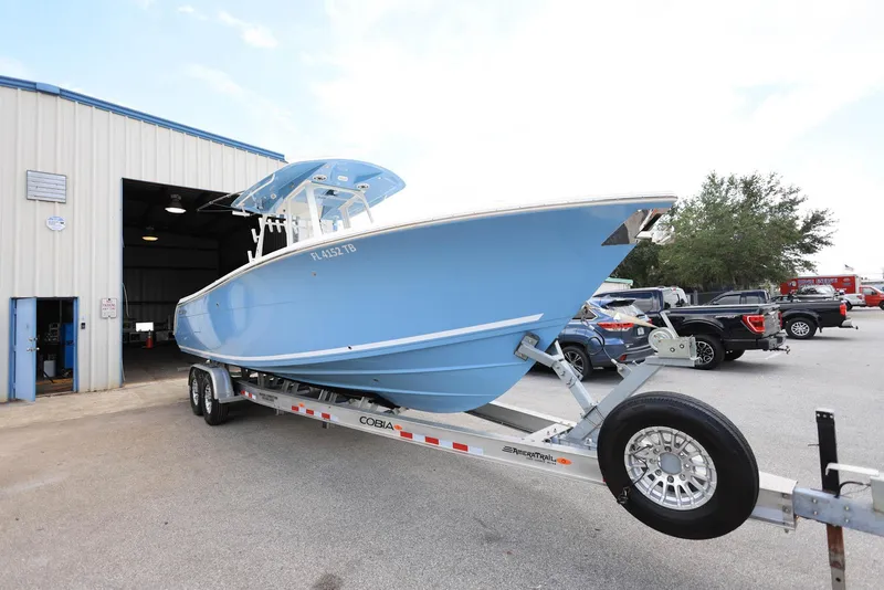 Slide: The Image of 2022 Cobia 301 Center Console boat on trailer outside a warehouse. - 4