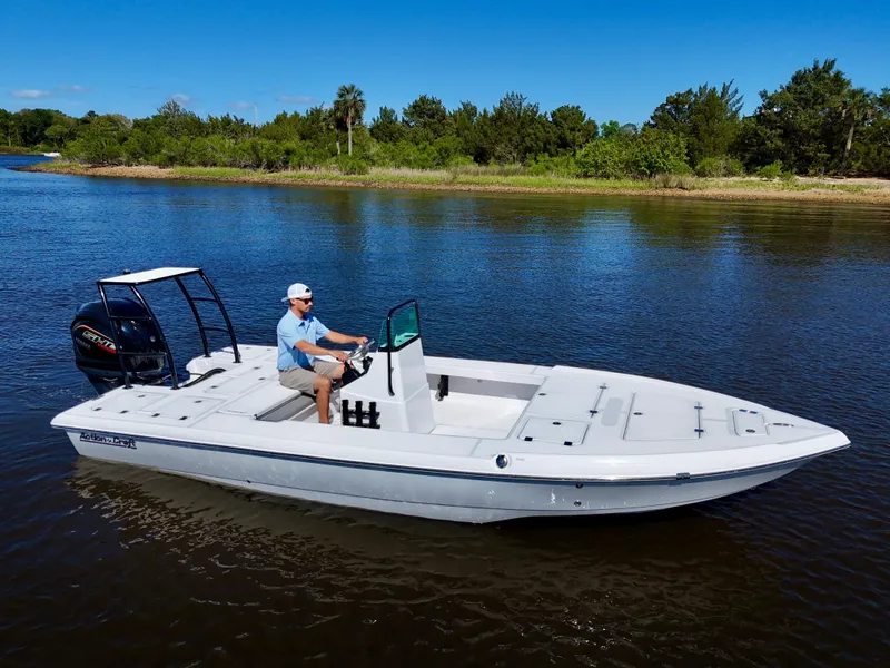 Slide: The Image of 2025 Action Craft 20 Flats boat cruising on a calm river with lush greenery. - 12