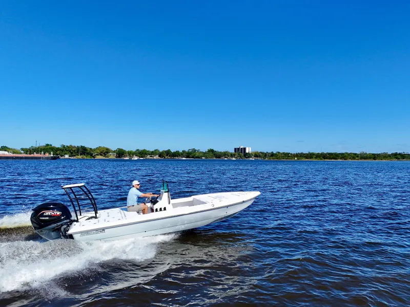 Slide: The Image of 2025 Action Craft 20 Flats boat cruising on a sunny day, blue sky, and calm waters. - 2