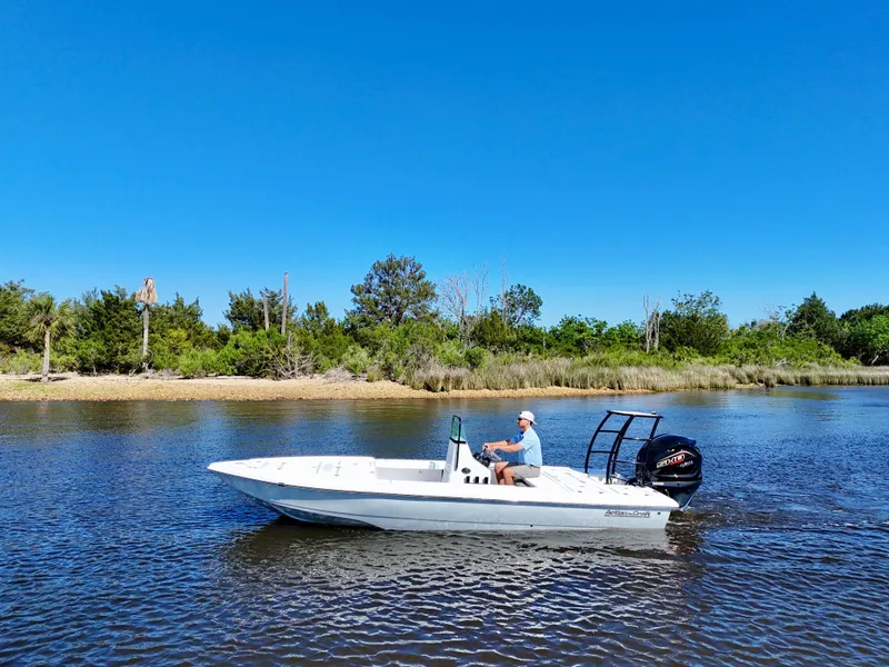 Slide: The Image of 2025 Action Craft 20 Flats boat cruising on a calm river under a clear blue sky. - 4
