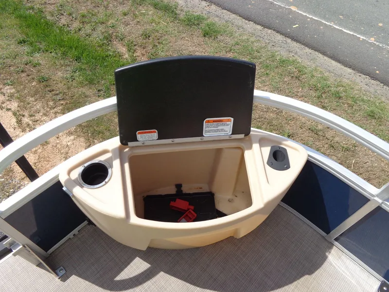 Slide: The Image of 2019 Sun Tracker Fishin' Barge 22 DLX storage compartment with cup holder and warning labels. - 13