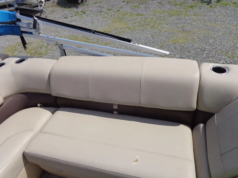 Slide: The Image of 2019 Sun Tracker Fishin' Barge 22 DLX beige seating with cup holders on a gravel surface. - 21