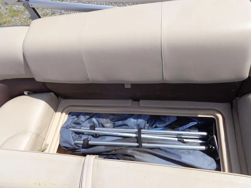 Slide: The Image of 2019 Sun Tracker Fishin' Barge 22 DLX storage compartment with folded equipment inside. - 22