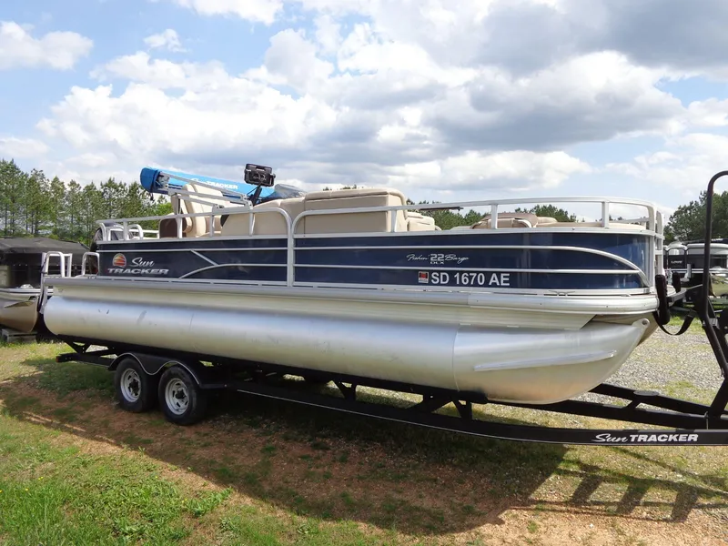 Slide: The Image of 2019 Sun Tracker Fishin' Barge 22 DLX pontoon boat on trailer, parked outdoors. - 3