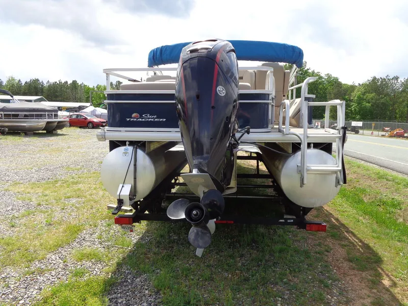 Slide: The Image of 2019 Sun Tracker Fishin' Barge 22 DLX pontoon boat with outboard motor, parked on grass. - 4