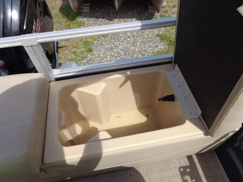 Slide: The Image of 2019 Sun Tracker Fishin' Barge 22 DLX storage compartment with open lid and beige interior. - 45
