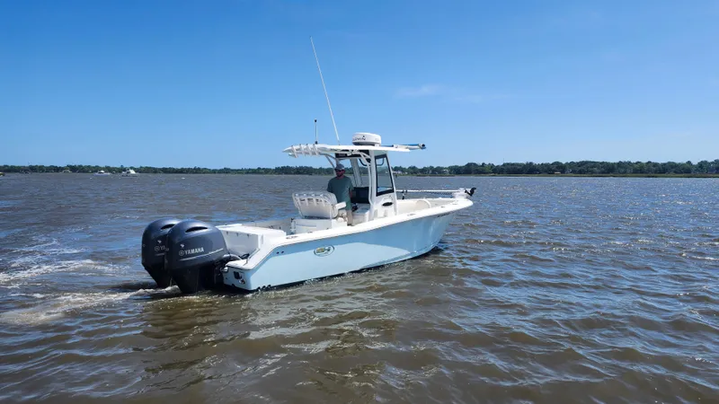 Slide: The Image of 2022 Sea Hunt Gamefish 25 boat cruising on open water under clear blue sky. - 27