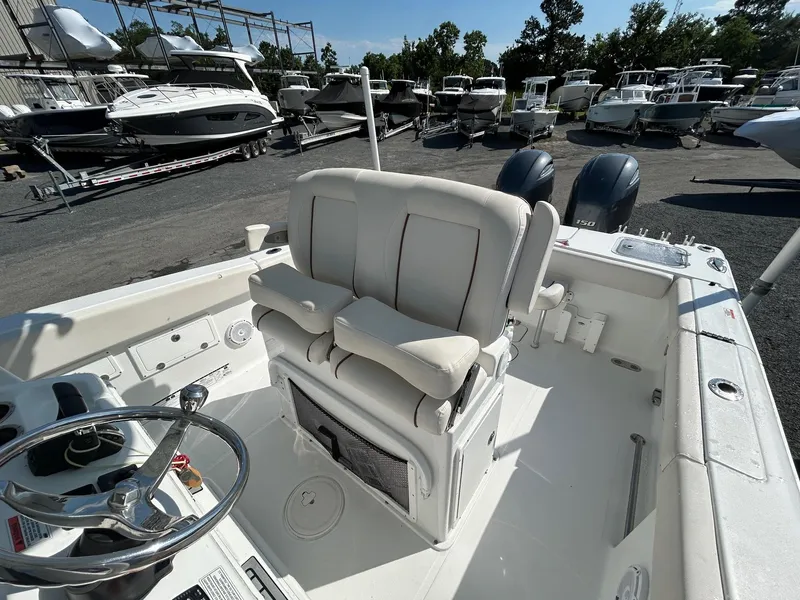 Slide: The Image of 2022 Sea Hunt Gamefish 25 boat interior with dual seats and steering wheel, docked among other boats. - 7