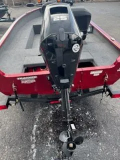Slide: The Image of 2025 Tracker Super Guide V-16 T boat with outboard motor, red exterior, parked on pavement. - 7