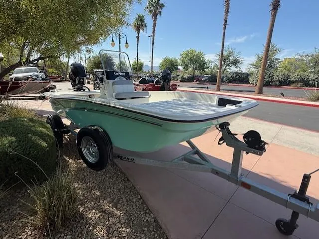 Slide: The Image of 2025 Mako Pro Skiff 15 CC boat on trailer, parked outdoors with palm trees. - 0