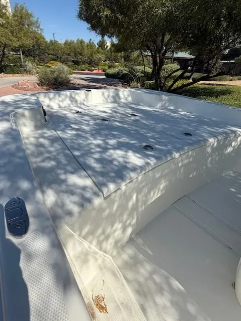 Slide: The Image of 2025 Mako Pro Skiff 15 CC boat, white deck, outdoor setting, dappled sunlight. - 6