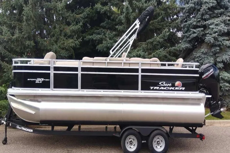 Slide: The Image of 2025 Sun Tracker SportFish 20 DLX pontoon boat on trailer, surrounded by trees. - 6