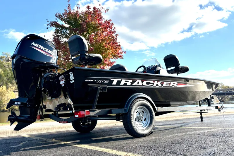 Slide: The Image of 2025 Tracker Pro 170 boat with Mercury engine, parked outdoors under a clear sky. - 80