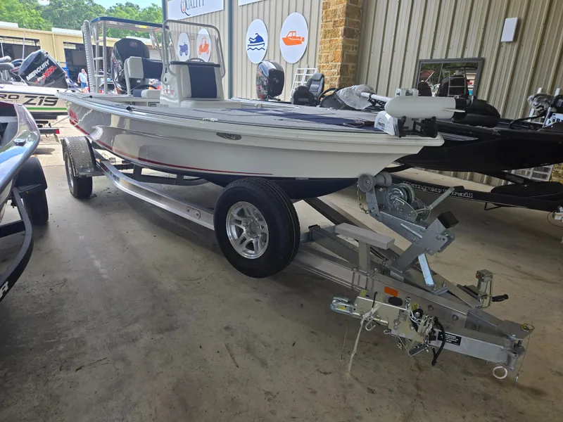 Slide: The Image of 2025 Mako 18 Pro Skiff Patriot Edition boat on trailer in showroom. - 1