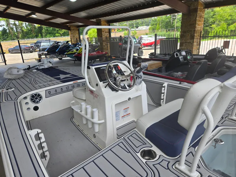 Slide: The Image of 2025 Mako 18 Pro Skiff Patriot Edition boat interior with steering console and seating. - 2