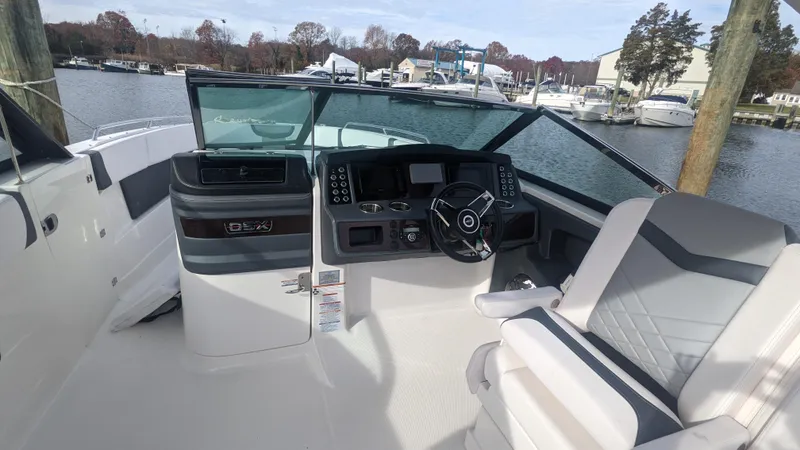 Slide: The Image of 2020 Chaparral 280 OSX boat cockpit with modern controls and seating, docked by a marina. - 15