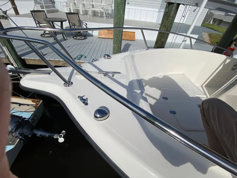 Slide: The Image of 2011 Pursuit C 200 Center Console boat docked, featuring stainless steel railings and spacious deck. - 12