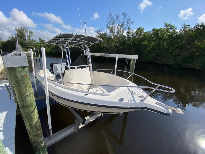 Slide: The Image of 2011 Pursuit C 200 Center Console boat docked on a lift by a river. - 2