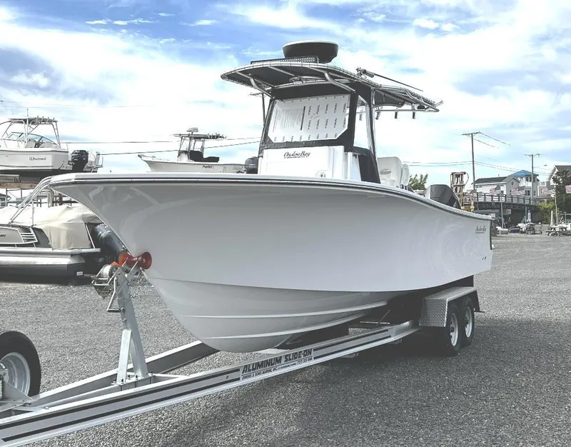 Slide: The Image of 2023 Onslow Bay 27 Offshore boat on trailer, parked outdoors under a cloudy sky. - 0