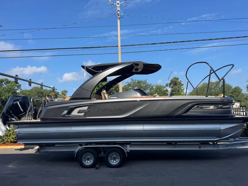 The Image of 2025 Avalon Excalibur 27' pontoon boat on trailer, sleek design, outdoor setting. - 1