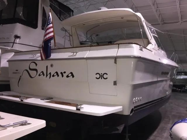 Slide: The Image of 1990 Sea Ray 390 Express Cruiser docked indoors, displaying "Sahara" name and American flag. - 40