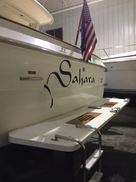 Slide: The Image of 1990 Sea Ray 390 Express Cruiser named "Sahara" with American flag, docked indoors. - 41