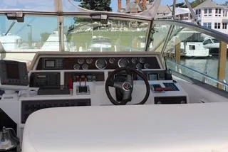 Slide: The Image of 1990 Sea Ray 390 Express Cruiser helm with gauges and controls, docked in a marina. - 48