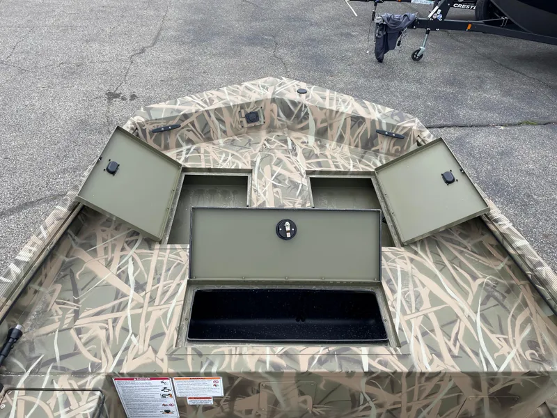 Slide: The Image of 2025 Crestliner 1760 Retriever Jon Deluxe boat with open storage compartments, camo design. - 11