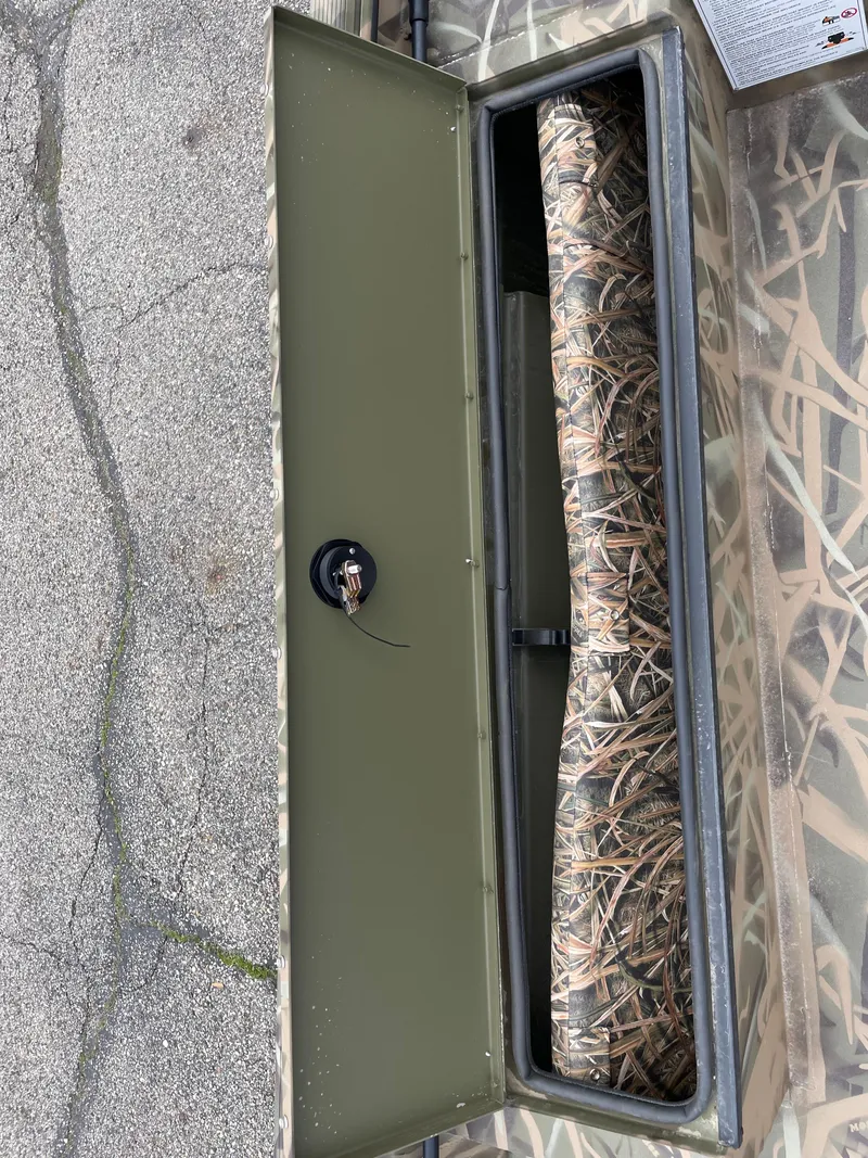 Slide: The Image of 2025 Crestliner 1760 Retriever Jon Deluxe boat storage compartment with camouflage interior. - 12