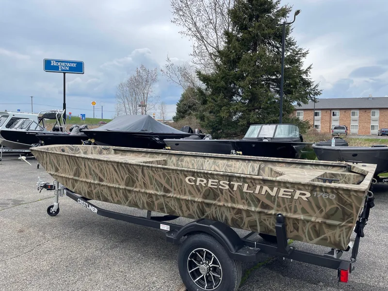 Slide: The Image of 2025 Crestliner 1760 Retriever Jon Deluxe boat on trailer, parked outdoors. - 2