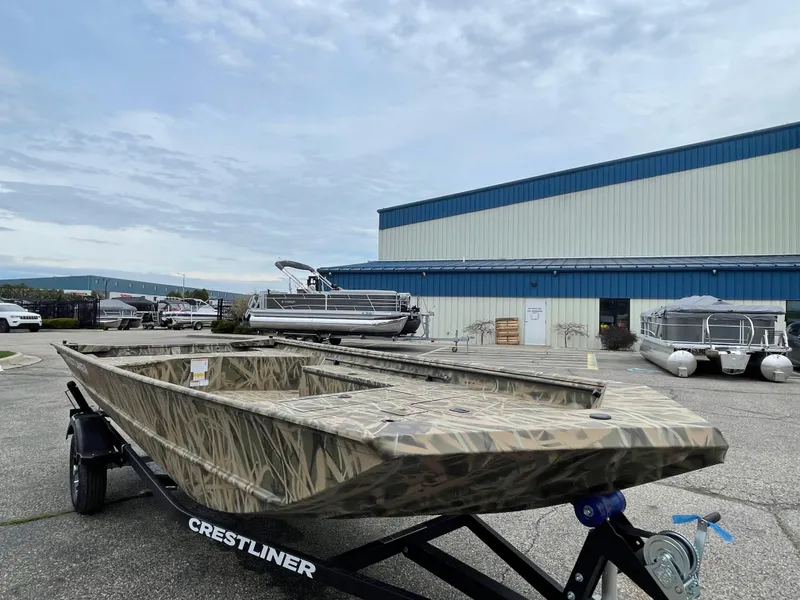 Slide: The Image of 2025 Crestliner 1760 Retriever Jon Deluxe boat on trailer, parked outside a warehouse. - 3