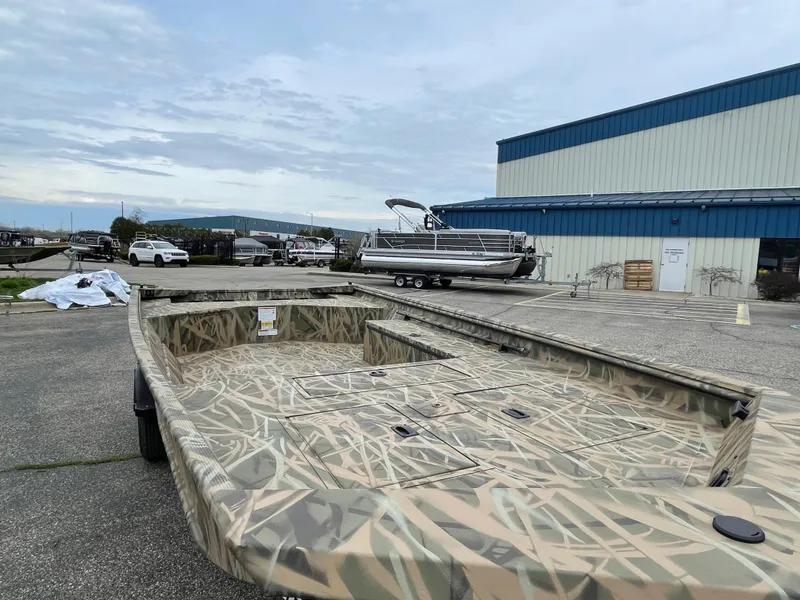 Slide: The Image of 2025 Crestliner 1760 Retriever Jon Deluxe boat with camouflage design in a marina setting. - 4