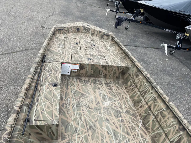 Slide: The Image of 2025 Crestliner 1760 Retriever Jon Deluxe boat with camouflage design on a concrete surface. - 5