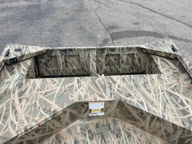Slide: The Image of 2025 Crestliner 1760 Retriever Jon Deluxe boat with camouflage pattern on pavement. - 7
