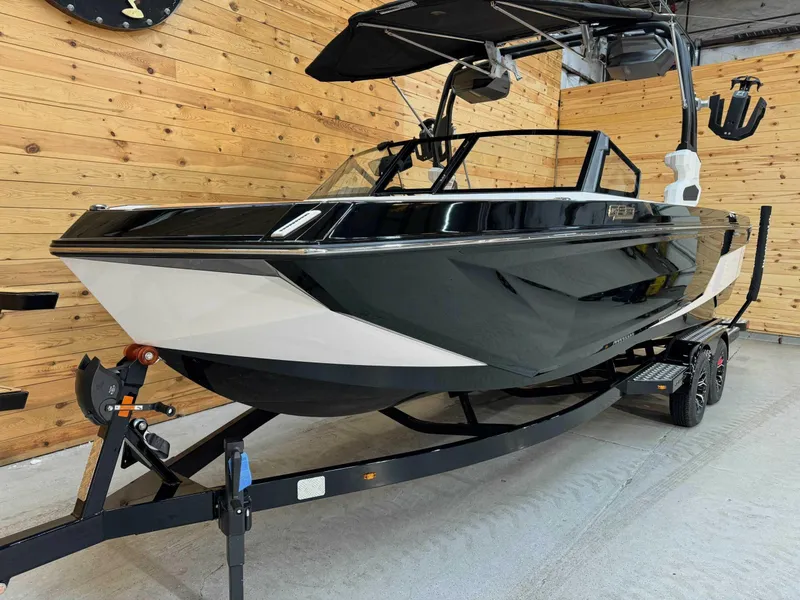 Slide: The Image of 2024 Nautique GS24 boat in showroom, black and white design, on trailer. - 2