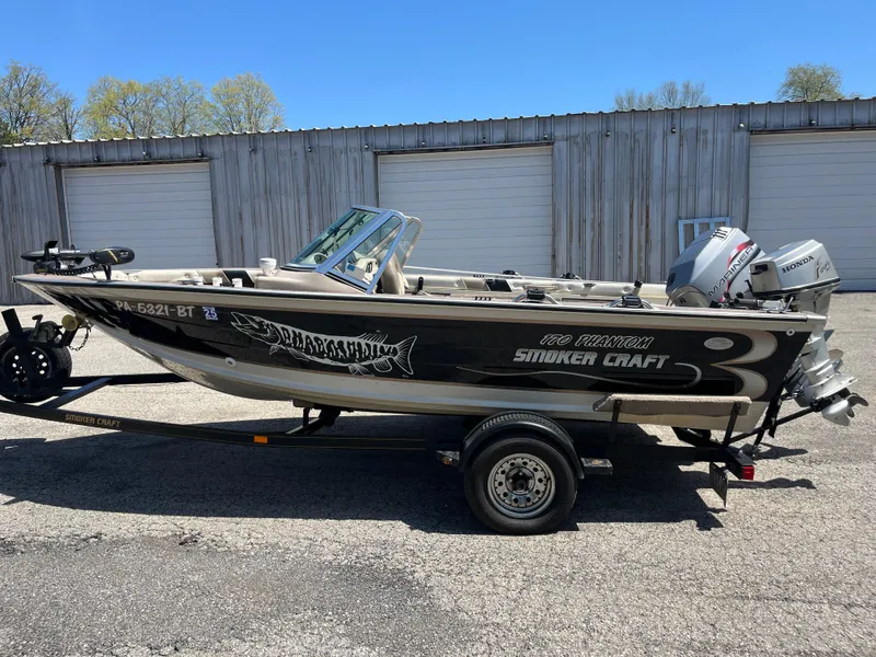 Slide: The Image of 1997 Smoker Craft 170 PHANTOM boat on trailer, parked outdoors near a wooden building. - 6