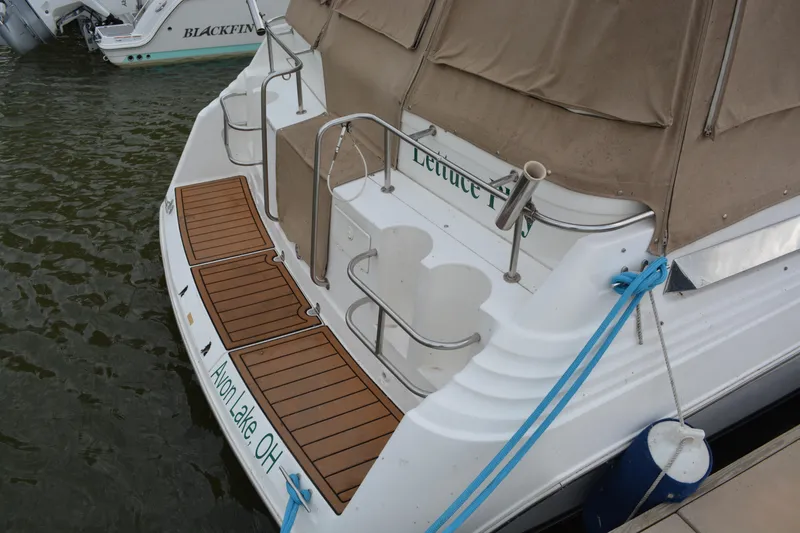 Slide: The Image of 1997 Cruisers Yachts 3120 Aria docked, featuring teak swim platform and beige canopy. - 7