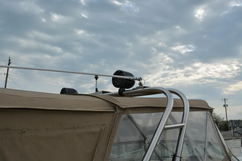 Slide: The Image of 1997 Cruisers Yachts 3120 Aria with canvas cover and ladder under cloudy sky. - 8