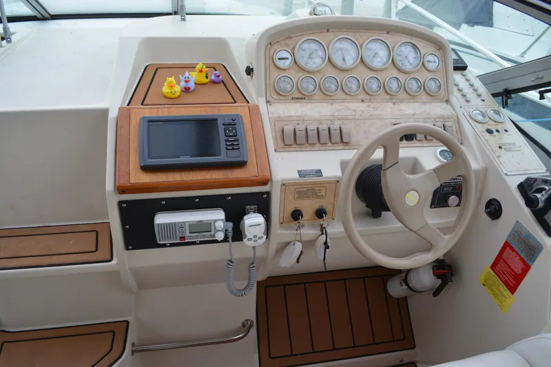 Slide: The Image of 1997 Cruisers Yachts 3120 Aria helm with gauges, steering wheel, and navigation equipment. - 10