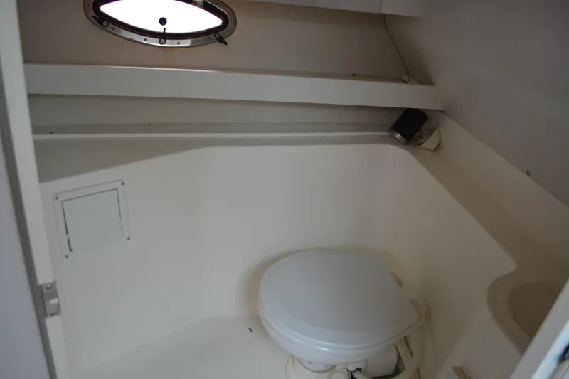 Slide: The Image of 1997 Cruisers Yachts 3120 Aria boat bathroom with compact toilet and porthole window. - 30