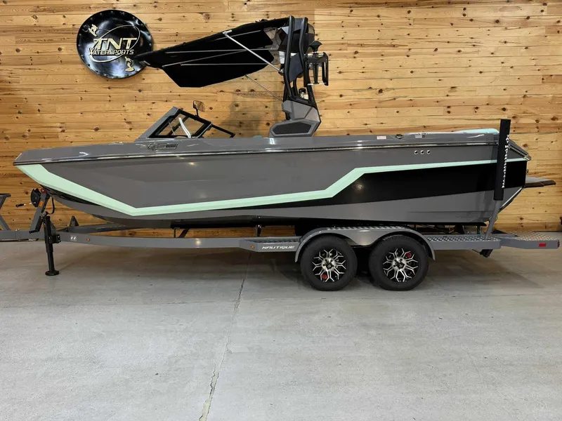 The Image of 2025 Nautique GS22 boat on trailer, gray with mint accents, displayed indoors. - 1