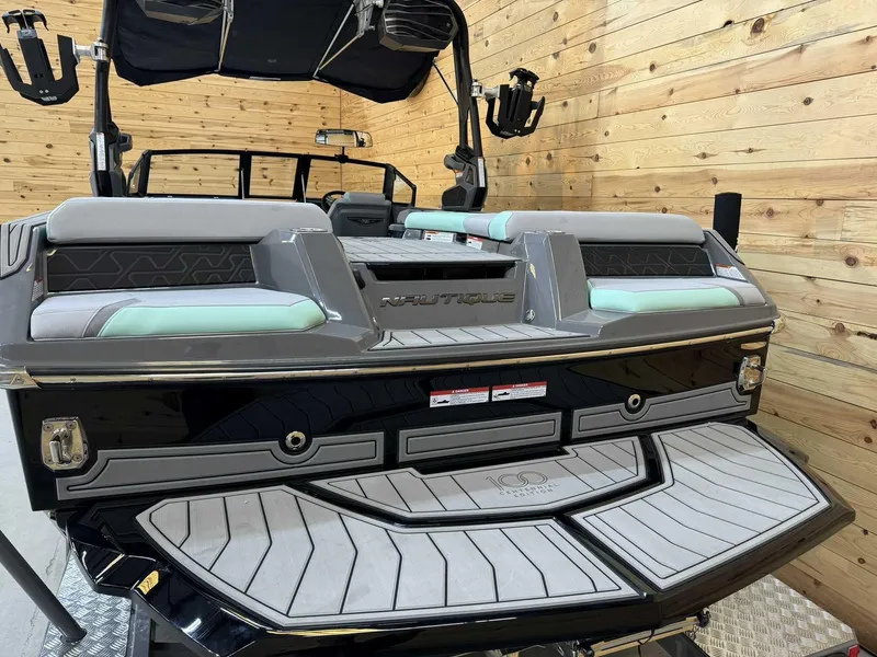 Slide: The Image of 2025 Nautique GS22 boat, rear view, in a wooden interior setting. - 3