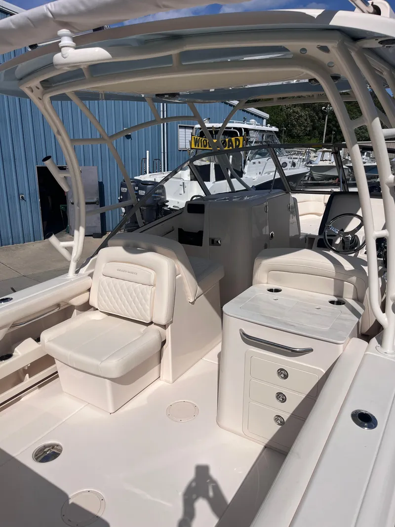 Slide: The Image of 2025 Grady-White Freedom 275 boat interior with seating and storage, docked near a blue building. - 10