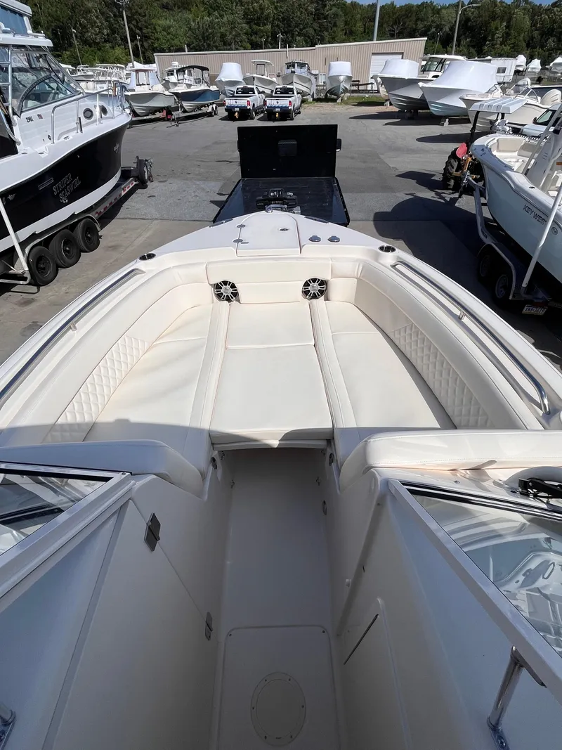 Slide: The Image of 2025 Grady-White Freedom 275 boat with spacious seating, docked among other boats. - 11