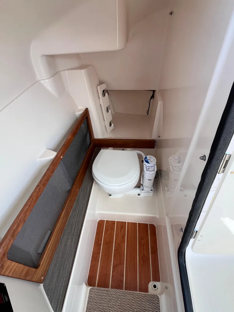 Slide: The Image of 2025 Grady-White Freedom 275 boat interior with compact toilet and wooden flooring. - 14