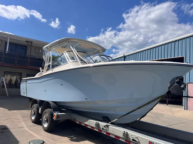 Slide: The Image of 2025 Grady-White Freedom 275 boat on trailer, parked outdoors under a blue sky. - 2
